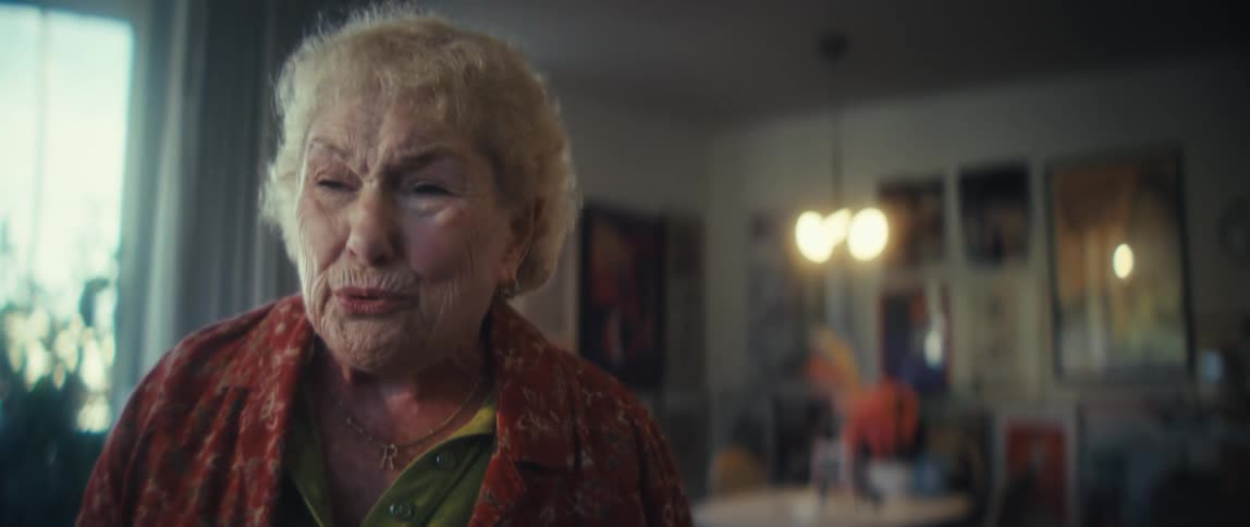 An elderly woman dances in her living room at midday excited