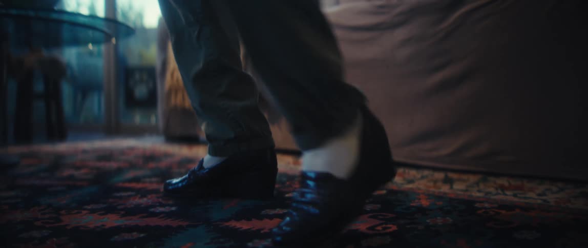 The video starts with a lowangle shot focusing on the feet in dark shoes of a person dancing or shuffling on a colorful patterned rugthe camera then quickly pans up to reveal an elderly woman smiling joyfully as she continues her move