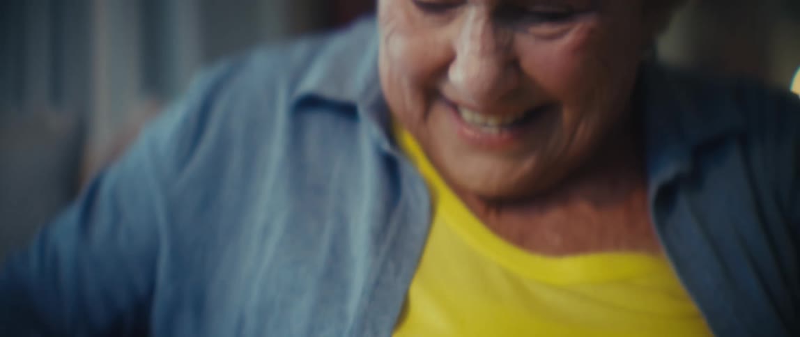 Elderly woman smiles while sitting on the couch and petting her dog