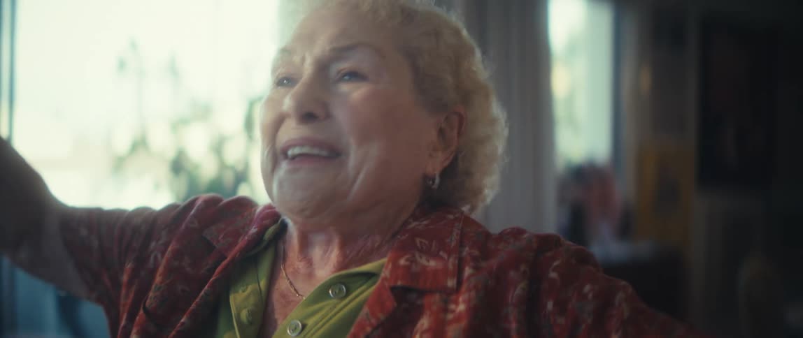 A joyful elderly woman passionately sings and dances in her home