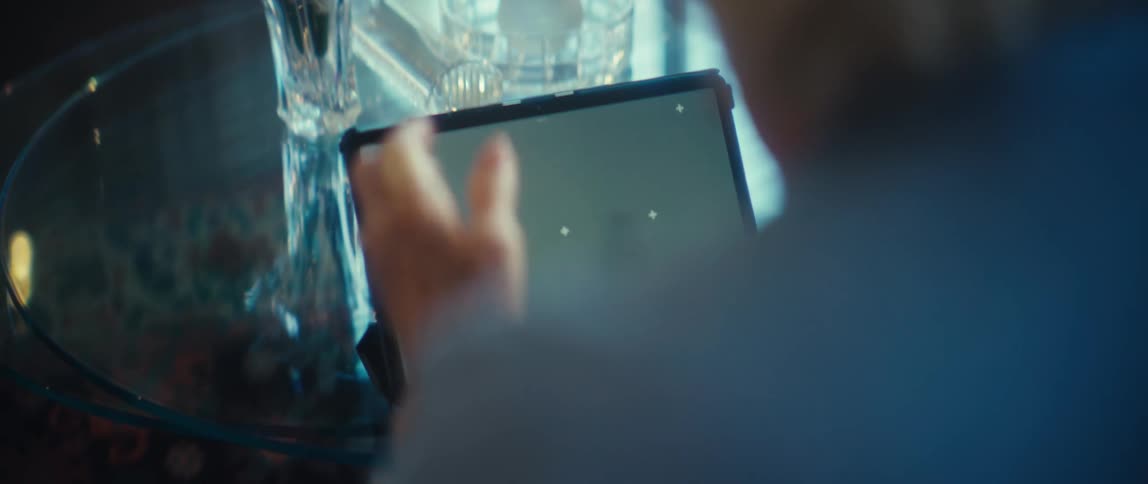 A person motions at a tablet with a green screen