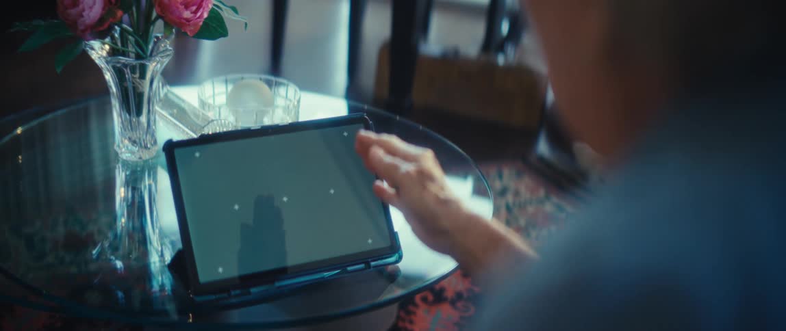 An elderly woman gestures expressively while having a conversation on a tablet with a green screen