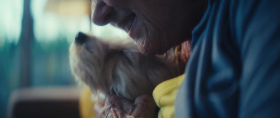 Elderly woman kissing a small dog while holding it lovingly