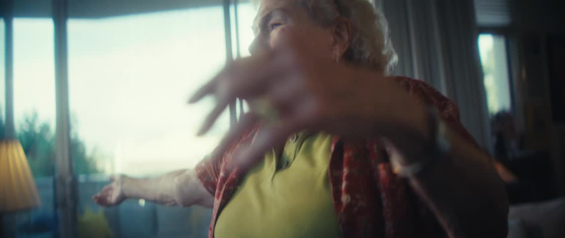 Woman smiles while dancing alone in her living room on a summer day