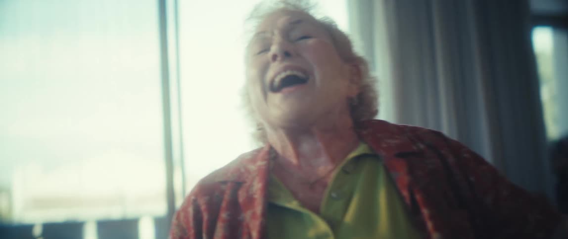 An elderly woman sings with great passion and joy in her brightly lit home