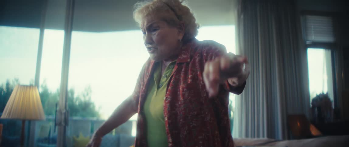 An elderly woman dances and sings in her living room at midday enjoying herself