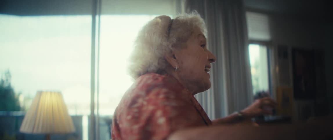 An elderly woman dances in her living room at midday excited