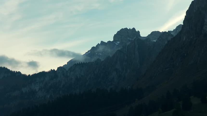 Rocky mountain range with peaks partially covered in snow at dawn