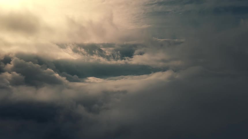 Drone shot of dense clouds illuminated by soft sunlight, looking like heaven