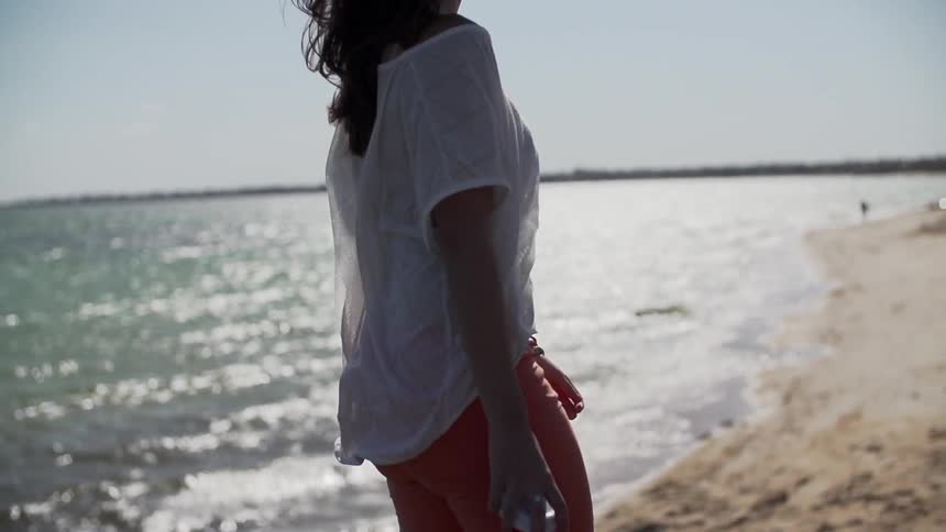 Woman walking alongside water with a cup