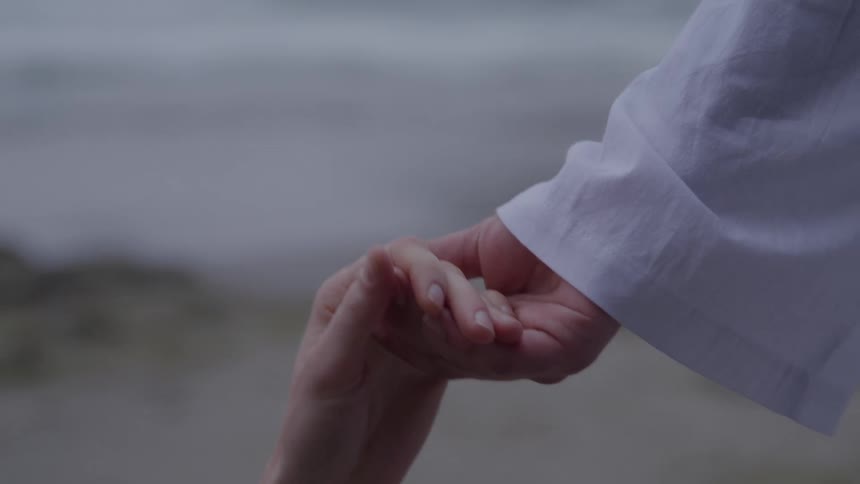 Outstretched hand helping another against a seaside backdrop