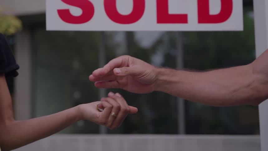 Man gives keys to a woman after completing a sale during the daytime