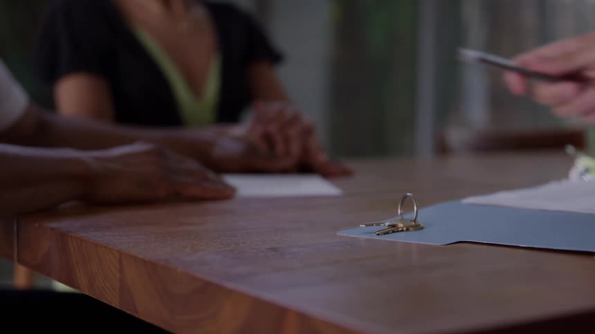 Couple signs documents in an office during a purchase