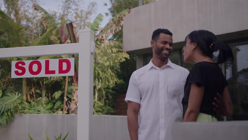The couple hug in front of a sold home