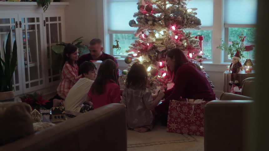Family opens presents at christmas while in their living room