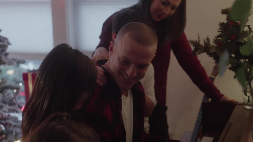 The father is playing the piano for his family