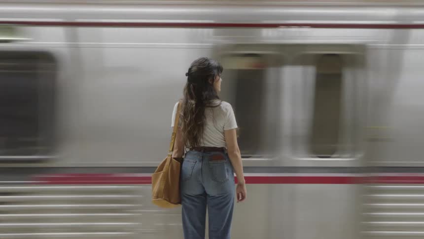 The woman watches the train pass on the platform
