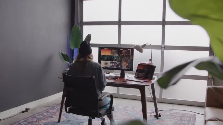 A young woman sits down at a workstation and puts on a pair of headphones