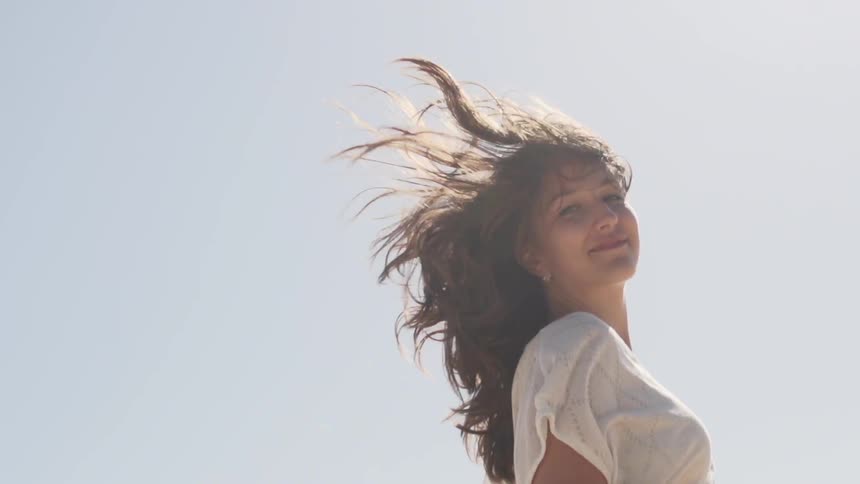 A woman running under a cloudy sky looks back