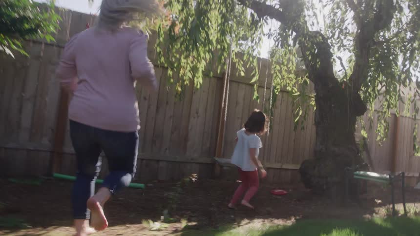 A mother chases her daughter to the swing