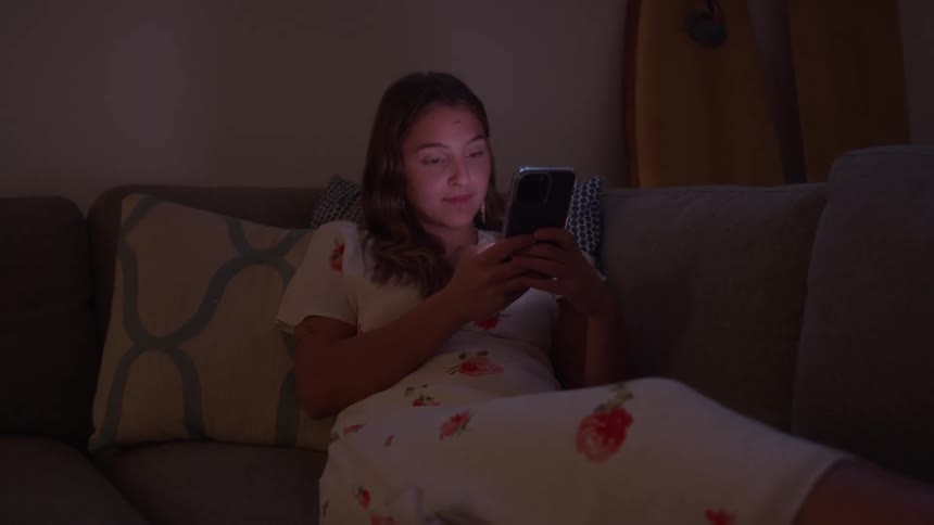 The woman is texting on the couch