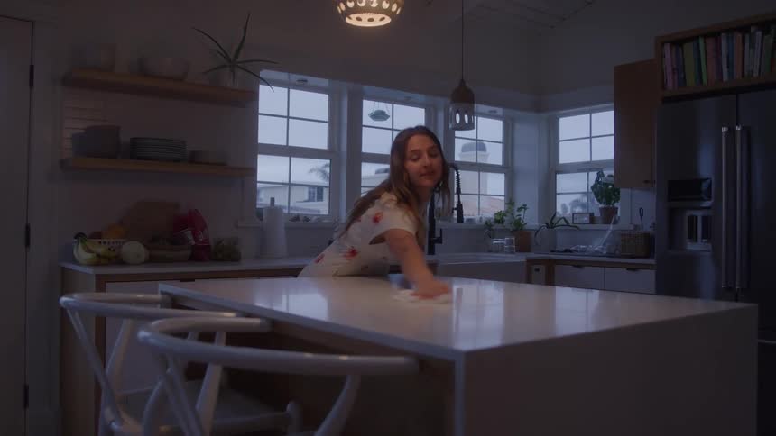 A woman wipes the countertop on her kitchen island