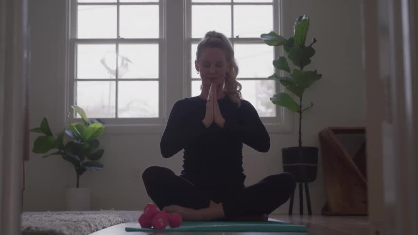 Woman smiles while sitting in a yoga position indoors during the daytime
