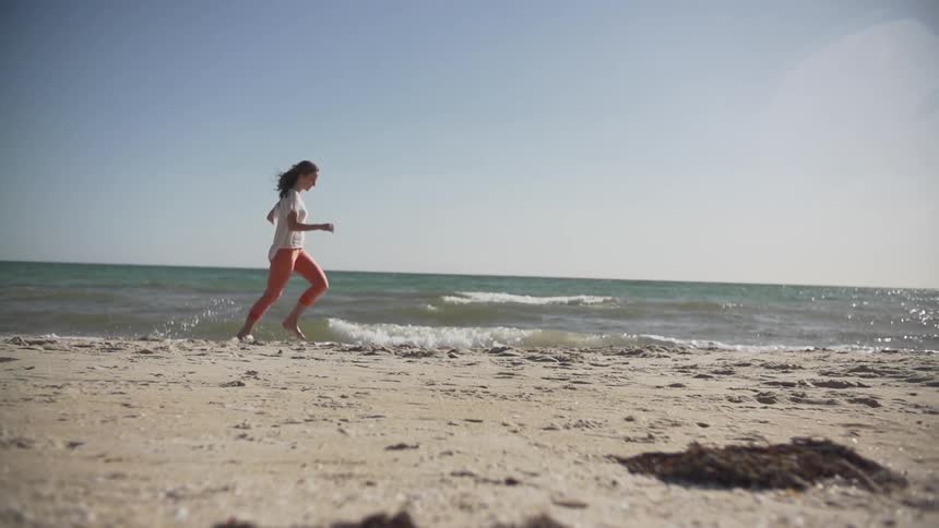 A woman runs across a beach