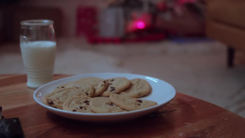 A persons hand picking up a cookie from a white plate full of them