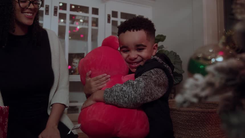 A mother watches her son hug a teddy bear