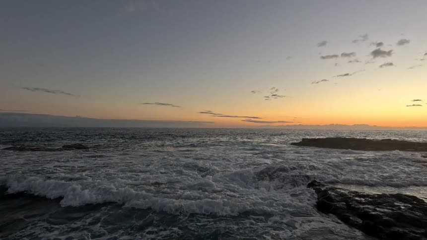 Waves crashing over the rocks during sunset on the ocean