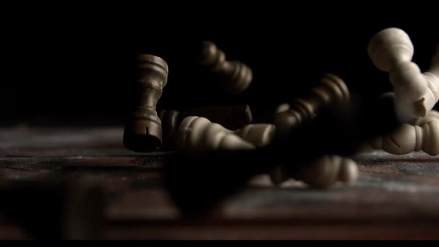 Several black and white chess pieces falling on a floor