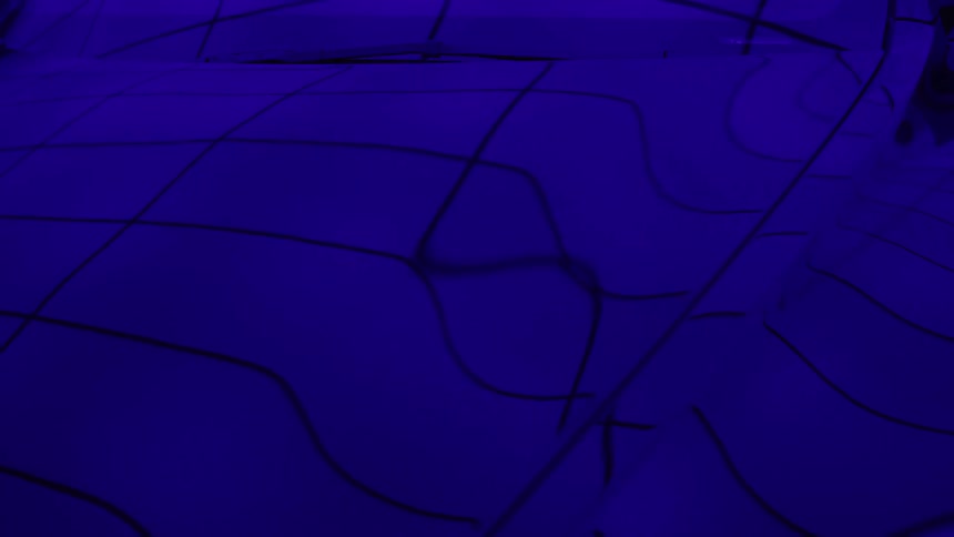 Abstract light and shadows create a dynamic dark blue pattern on the curved hood of a vehicle