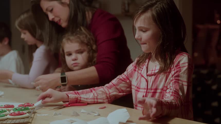 Woman and children making cookies and christmas crafts at the kitchen table