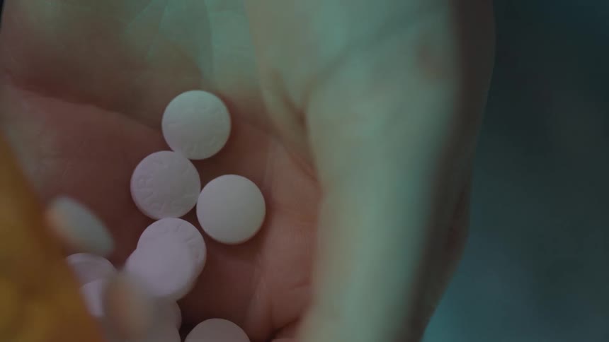 White pills being poured into the palm of a hand