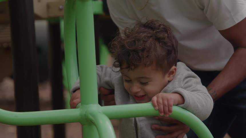 Father helps his young son on the playground on an autumn day