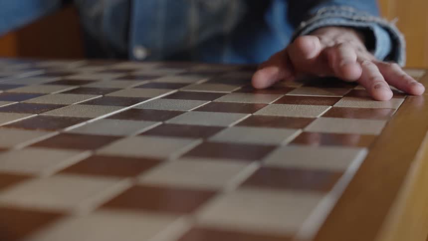 Man sitting at a table with a checked tabletop taps his fingers