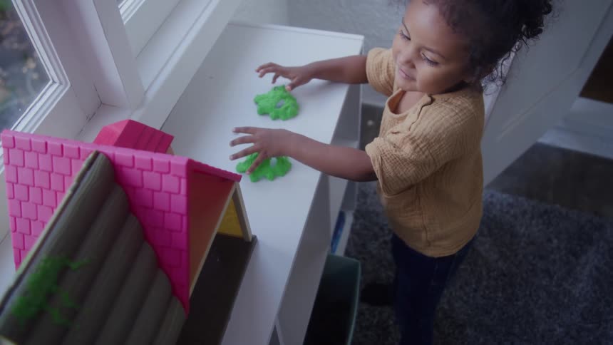 A child plays with a toy by the window at midday