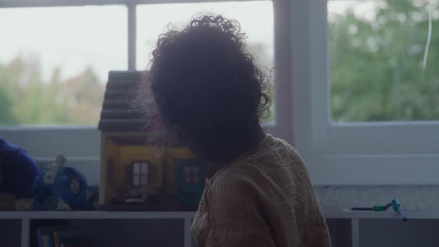 Girl plays with a dollhouse near the window at home on an autumn day