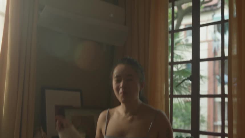 Woman smiles while holding a bowl and dancing alone at home