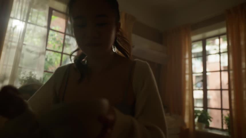 A teenage girl walks toward the camera holding a small bowl and spoon smiles then turns around and begins to eat the food from the bowl