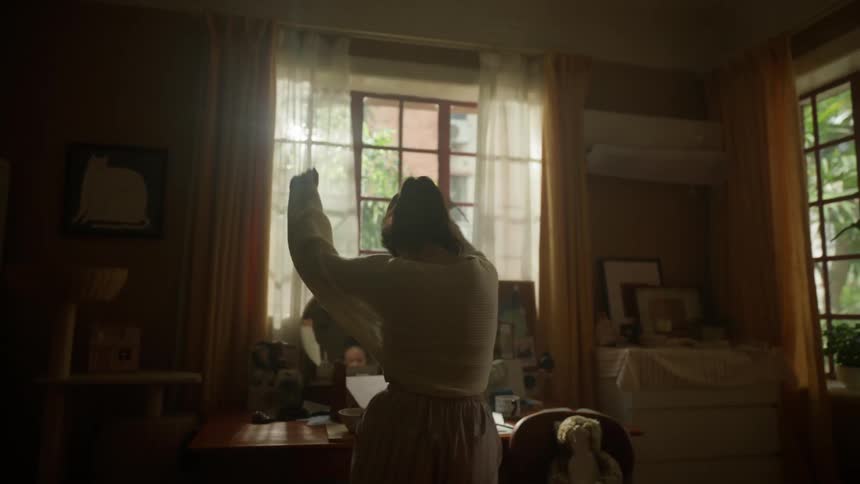 Woman watches herself in the mirror while dancing in her bedroom on a summer day
