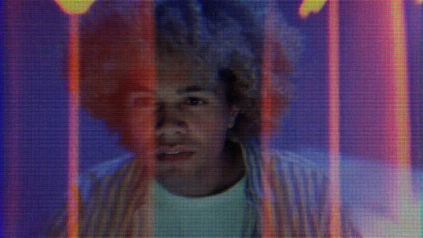 Man appears through a screen with visible pixel patterns and colored lights in the background