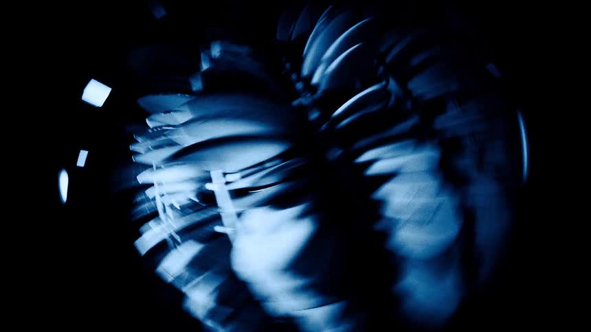 An object with multiple blades spins rapidly in a dark atmosphere its motion creating a blur of sharp edges