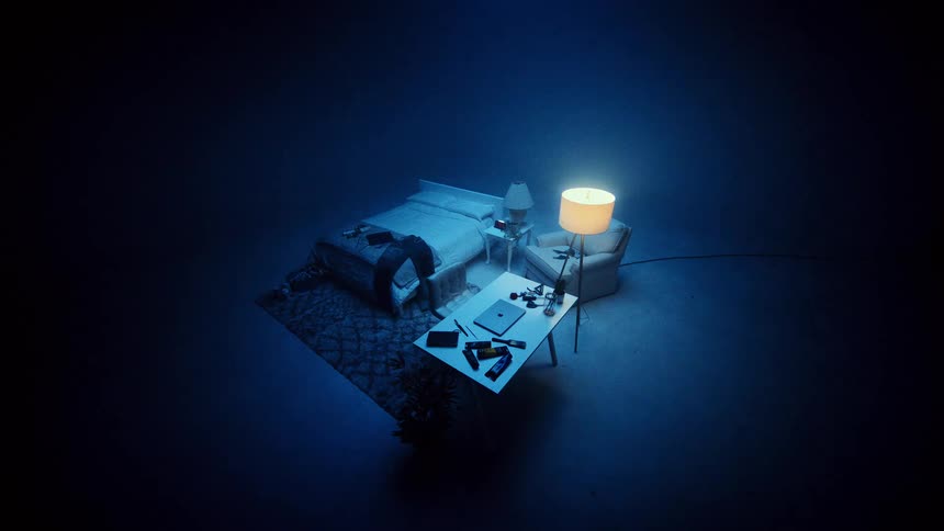 Bedroom lit by a soft yellow light featuring a bed desk and lamp in a dark blue setting