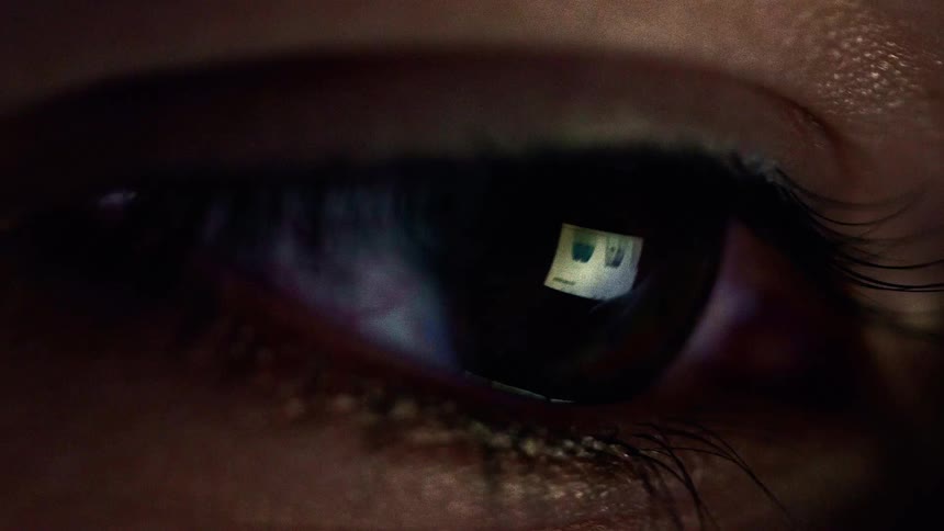 Reflection of a glowing screen captured in a closeup of a human eye