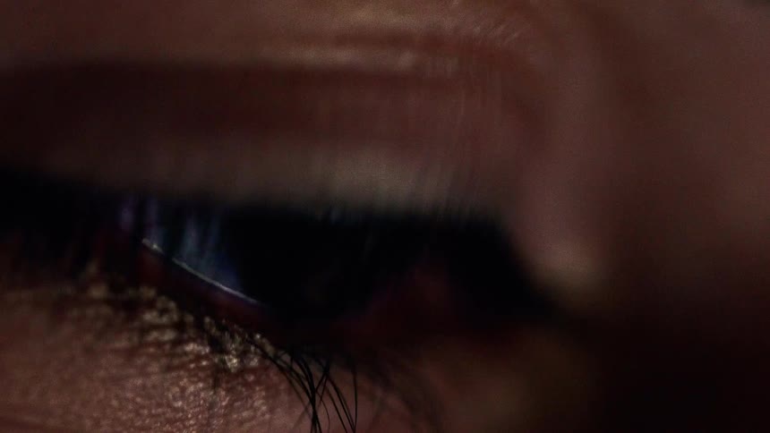 Reflection of a colorful screen appears in the pupil of an eye in closeup