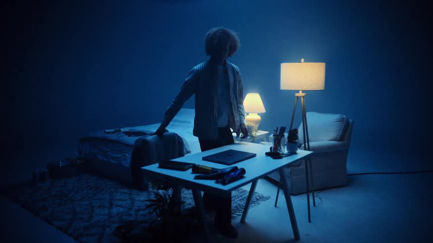 The man opens his laptop at the desk