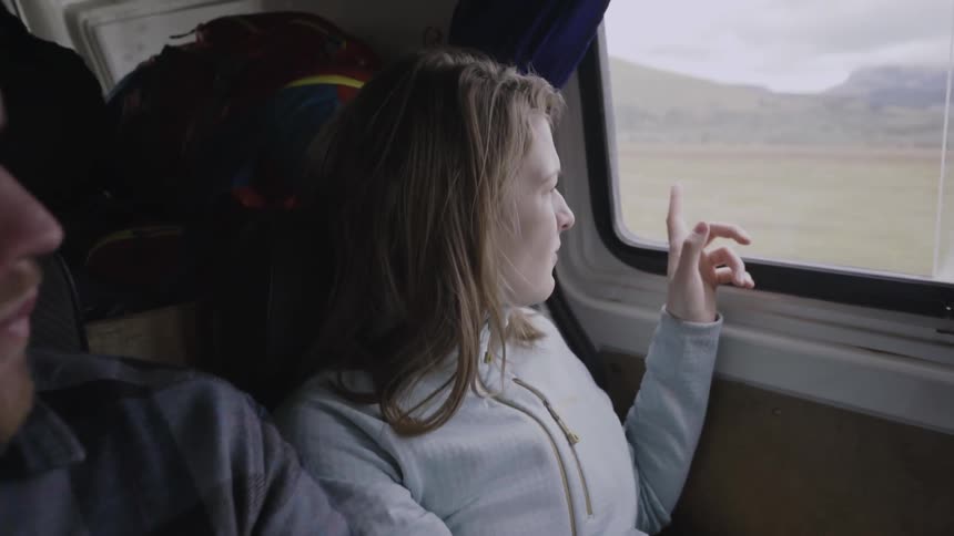 A man and woman look out the window of a moving vehicle