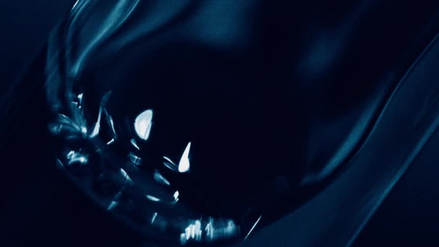 A closeup shot of a dark blue substance shows the surface shifting with bright white reflections running across the moving liquid